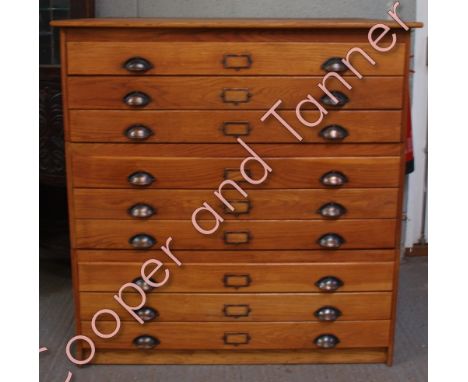 An early 20th Century light oak sectional map chest of nine long drawers with original metal cup handles and metal index hold