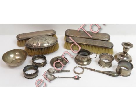 A collection of four silver napkin rings; a silver mustard pot; a silver rim from a bottle; four silver backed brushes; a loa
