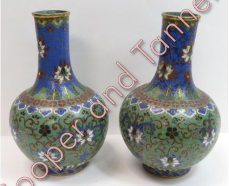 A pair of Japanese cloisonné bottle shaped vases having trailing floral and foliate decoration on a light green ground 23cms 