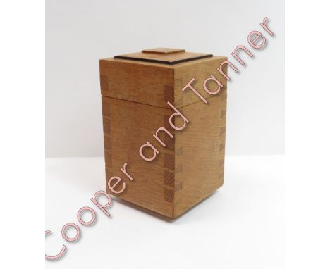 An Arts and Crafts Cotswold School oak tea caddy having lift-off stepped cover, with exposed dovetail joints and low pedestal