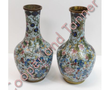 A pair of Japanese cloisonné bottle vases with trailing prunus and butterfly decoration on light blue ground, 16cms high