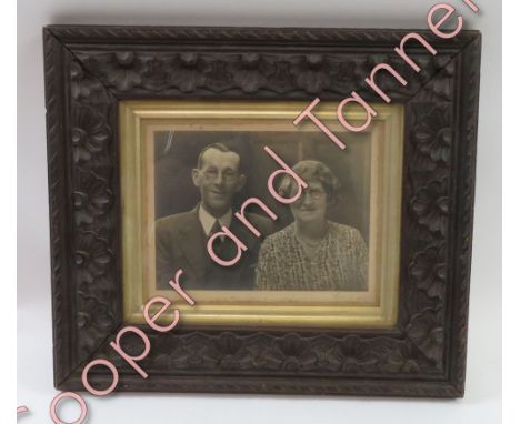 A late 19th/early 20th Century carved wood frame containing a photographic portrait
