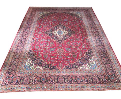 FINE KASHAN CARPET, 388cm x 293cm, pendant medallion on a ruby field of palmettes and vines within quarter medallion spandrel