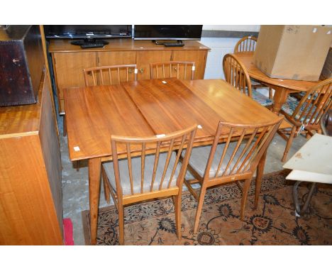 A mid century walnut extending dining table with one leaf together with four matching stick back chairs and a sideboard.