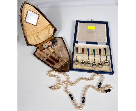 A boxed set of 6 teaspoons with coloured enamel decoration; a part fitted shield shaped sewing set 