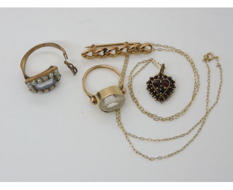 A collection of yellow metal items to include a clear gem set ring, a curblink brooch, a garnet heart shaped pendant, chain a