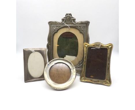 An Edwardian silver photo frame, of shaped form, the frame surrounded by moulded floral borders, surmounted by a blank oval c