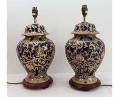 A pair of ceramic table lamps in the Chinese style with gilding against cobalt blue ground, each on circular wooden base (min