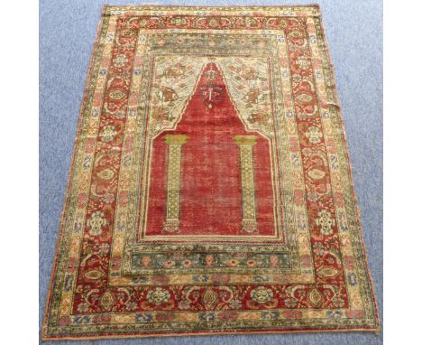 A Turkish silk prayer rug (third quarter 19th century); red mihrab with two vertical columns on a plain red field, the main d