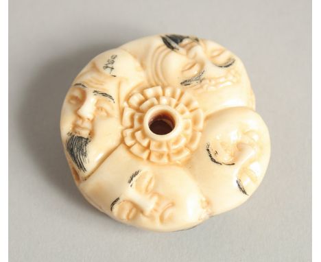 A CHINESE CARVED BONE NETSUKE with faces. 1.5ins diameter.