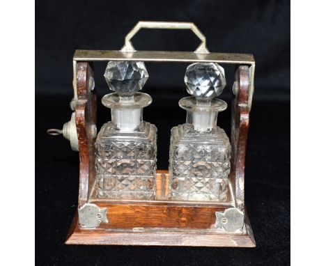 A MINATURE TWO BOTTLE SCENT FLASK TANTALUS  the EPNS frame stamped 'THE TANTALUS', 13cm wide 14.5cm high overall Condition Re