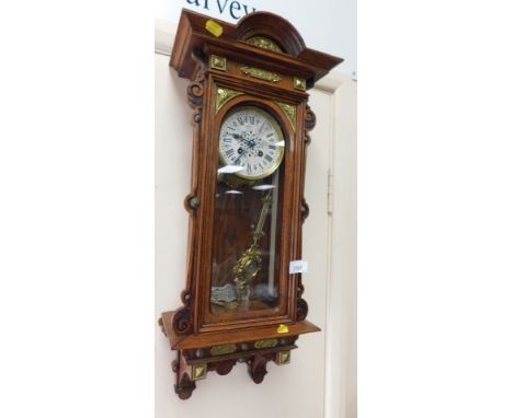 A cased wall clock, with brass decoration, circular silvered dial bearing Roman numerals, eight day movement, 63cm high. 