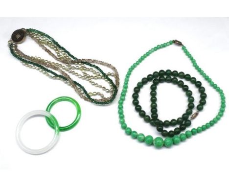 A group of oriental jewellery includes green hardstone beaded necklaces and treated jade bangles