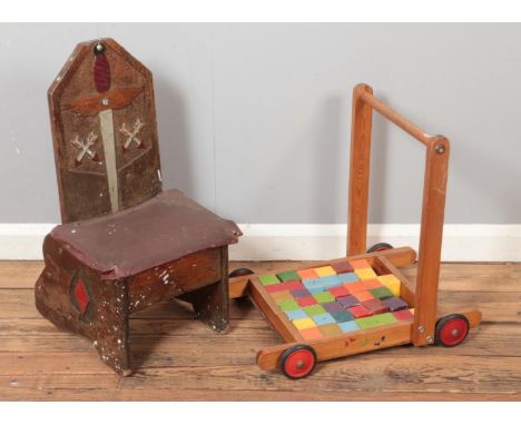 A small wooden child's chair decorated with swords and arrows with a vintage push trolley with blocks  