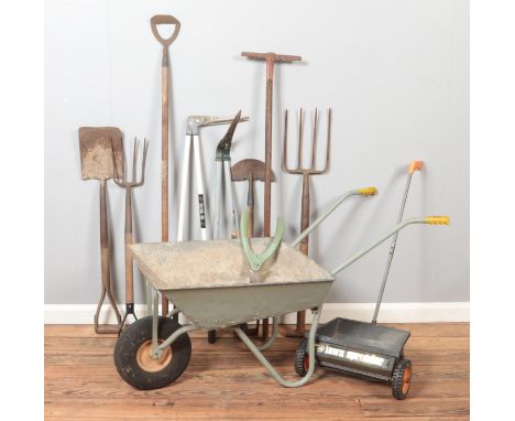 A collection of garden tools. Includes wheel barrow, lawn spreader, Wilkinson Sword etc.  