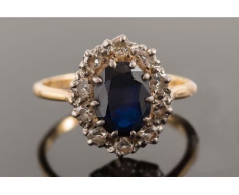 An 18ct gold, sapphire and diamond oval cluster ring:, the oval sapphire within a surround of circular, brilliant-cut diamond