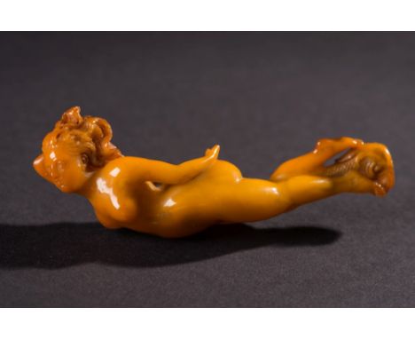 A late 19th century carved amberoid pipe stem:, in the form of a nude female figure, with flowing hair and dolphin decoration