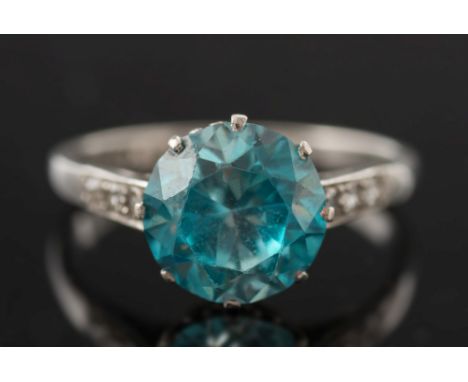 An 18ct white gold, platinum and blue zircon single-stone ring:, the circular blue zircon 9.5mm diameter in a scroll-pierced 