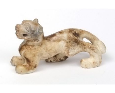 A Chinese carved jade figure of a Buddhist lion: the stone of mottled grey and brown colour, 6.5 cm long.
