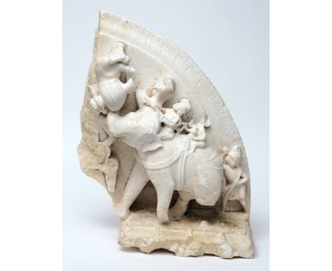 An Indian carved marble plaque:, of semi arched outline, decorated with a scene of an elephant carrying urns in its trunk and