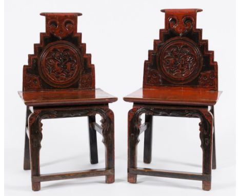 A pair of Chinese red and black lacquer side chairs:, the stepped backs with paper scroll top rails and roundels decorated wi