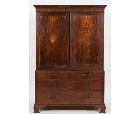 A George III mahogany and inlaid linen press:, the upper part with a moulded dentil cornice, fitted with sliding trays, enclo
