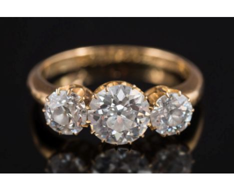 An early 20th Century gold and diamond mounted three-stone ring: with central round, brilliant-cut diamond approximately 7.4m