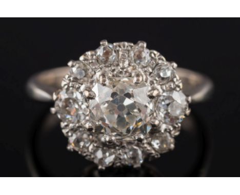 A diamond mounted circular cluster ring: with central, cushion shaped old brilliant-cut diamond estimated to weigh  0.80ct, w
