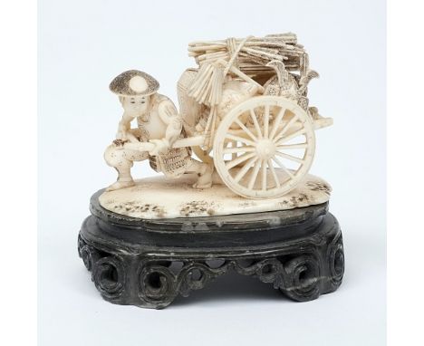 A Japanese carved ivory okimono: in the form of a Samurai warrior pulling a handcart loaded with his equipment including an o