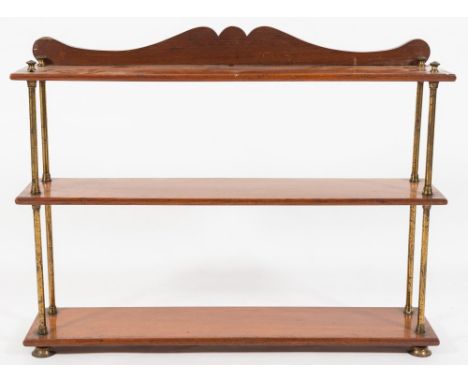 A 19th Century teak three tier open bookcase:, the rectangular detachable shelves on brass column uprights, having a shaped l