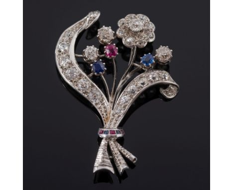 A diamond, sapphire and ruby mounted floral spray brooch: with single flower head, ribbons and buds, claw and pave-set with r