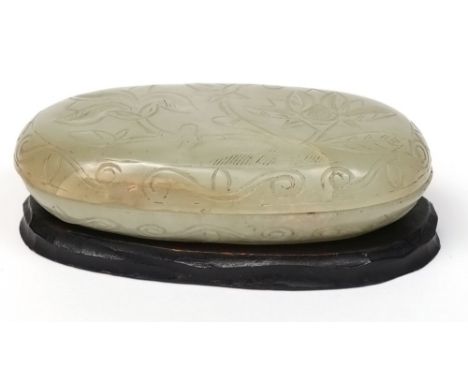 A Chinese jade box and cover: of flattened ovoid form, the cover carved with a flowering shrub within a border of double scro