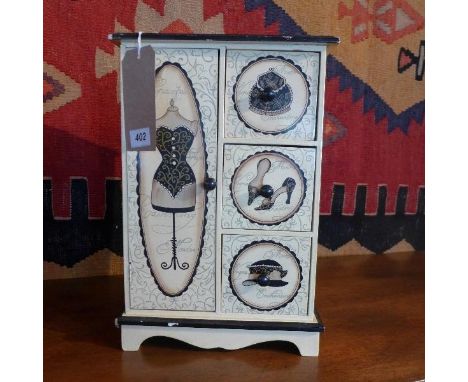 A jewellery box in the form of a cream painted wardrobe, the drawers and cupboard door decorated with shoes, hats, purses and