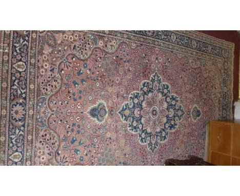 A Kashan carpet, with central floral medallion, on a salmon pink ground, surrounded by floral motifs, contained by floral bor