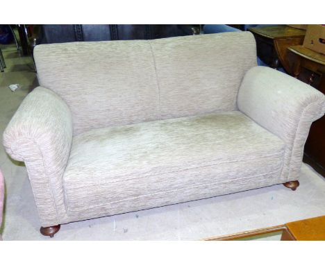 A 2 seater sofa in fawn upholstery, wood feet and castors