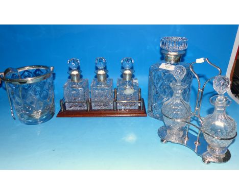 A cut crystal decanter with silver rim; 3 silver rim bitters bottles with hallmarked silver bottle labels, on galleried stand