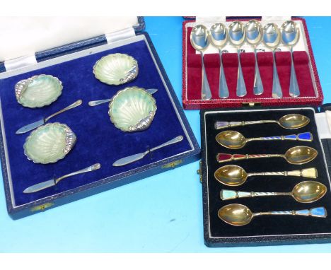 A cased set of 6 silver coffee spoons; a cased set of 4 shell butter dishes; a cased set of 6 gilt and enamel coffee spoons