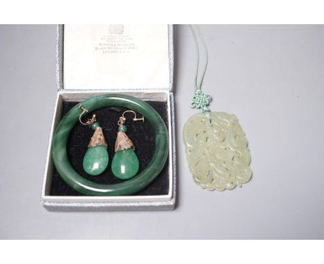 A Chinese carved bowenite jade pendant, a pair of green paste earrings and a green paste bangle.