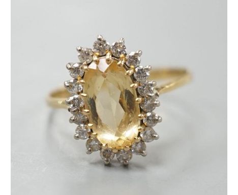 A modern yellow metal, yellow topaz and diamond set oval cluster ring, size T, gross weight 3.7 grams.