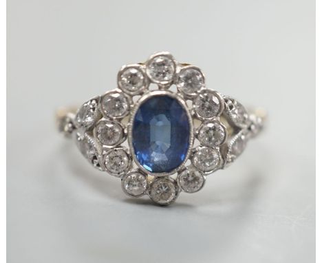 A yellow metal, sapphire and diamond set oval cluster ring, size  T, gross weight 3.8 grams.