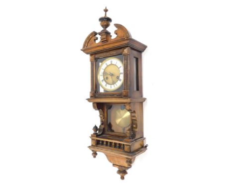 A late 19th/early 20thC Junghans wall clock, in a walnut case with shaped crest with a part enamel dial with visible pendulum