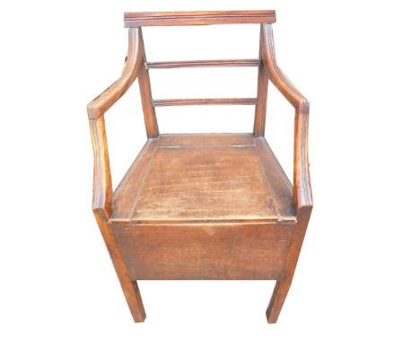An early 19thC oak commode chair, with a slatted back, shaped arms, 51cm wide. This lot is located at Oundle, Near Peterborou