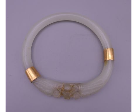 A Chinese gold mounted jade bangle carved with dragon heads. 8.5 cm exterior diameter and 6.75 cm interior diameter. 