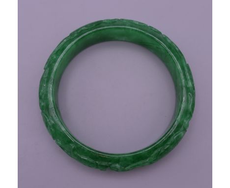 A carved jade bangle. 7.5 cm exterior diameter, 6 cm interior diameter.