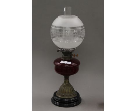 A Victorian oil lamp with red glass reservoir. 51 cm high.