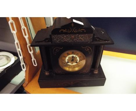 A Victorian slate mantel clock having brass and enamelled dial with embossed cherub decoration, plaque and Corinthian columns