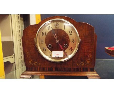 An Art Deco mahogany cloud shaped mantel clock having scrolling inlay with silvered chapter ring and Arabic numerals