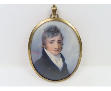 An early 19th century oval miniature portrait on ivory of a young gentleman wearing a dark blue coat, in gold metal pendant m