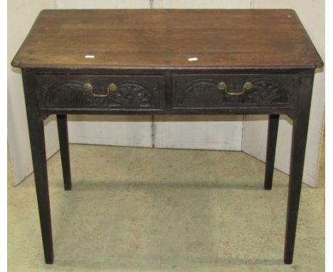 An antique oak side table fitted with two frieze drawers with carved detail raised on square tapered supports