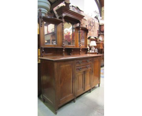 A late Victorian oak mirror backed sideboard, the base enclosed by an arrangement of cupboards and drawers with fielded panel